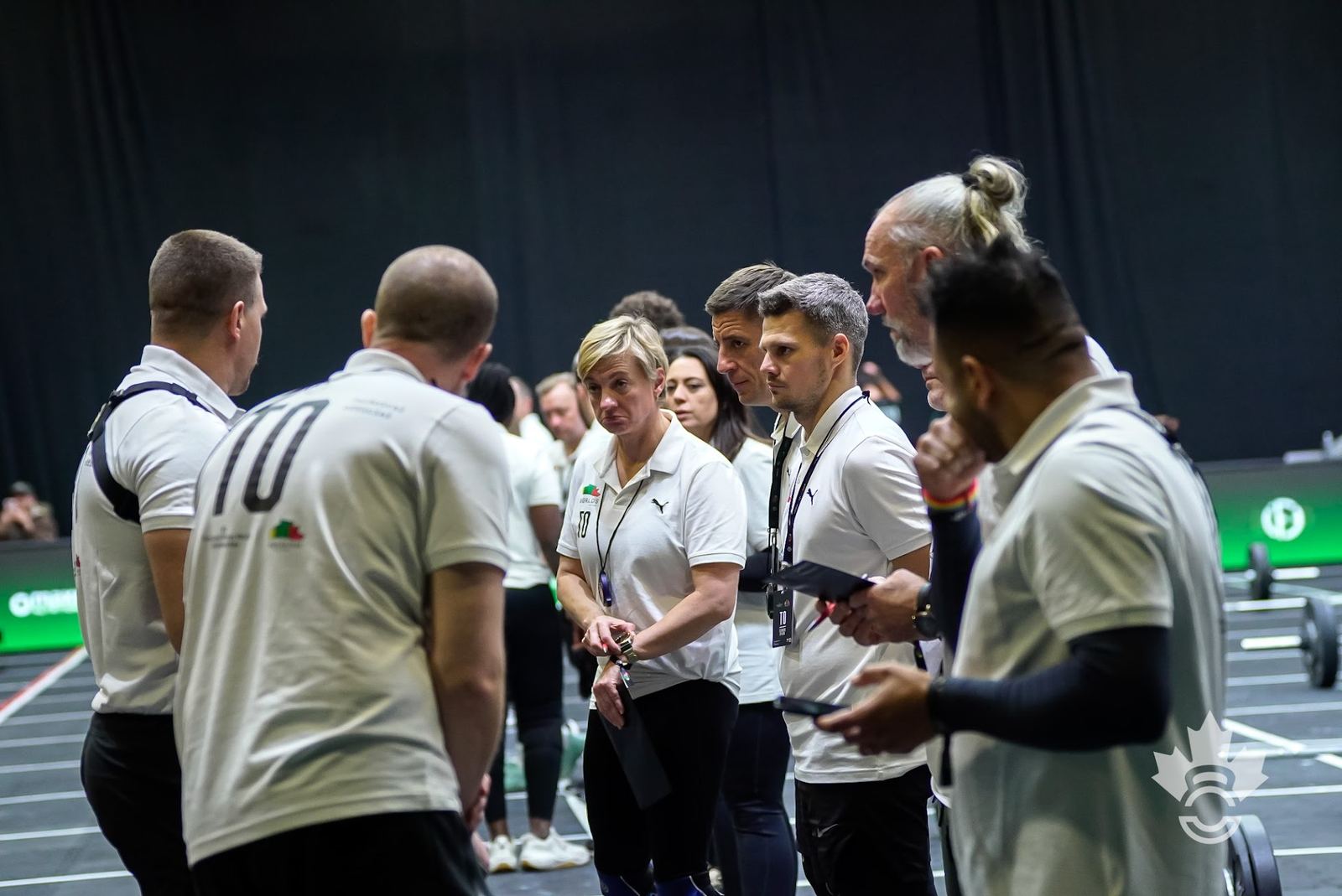 A group of Technical Officials in discussion on the floor between heats