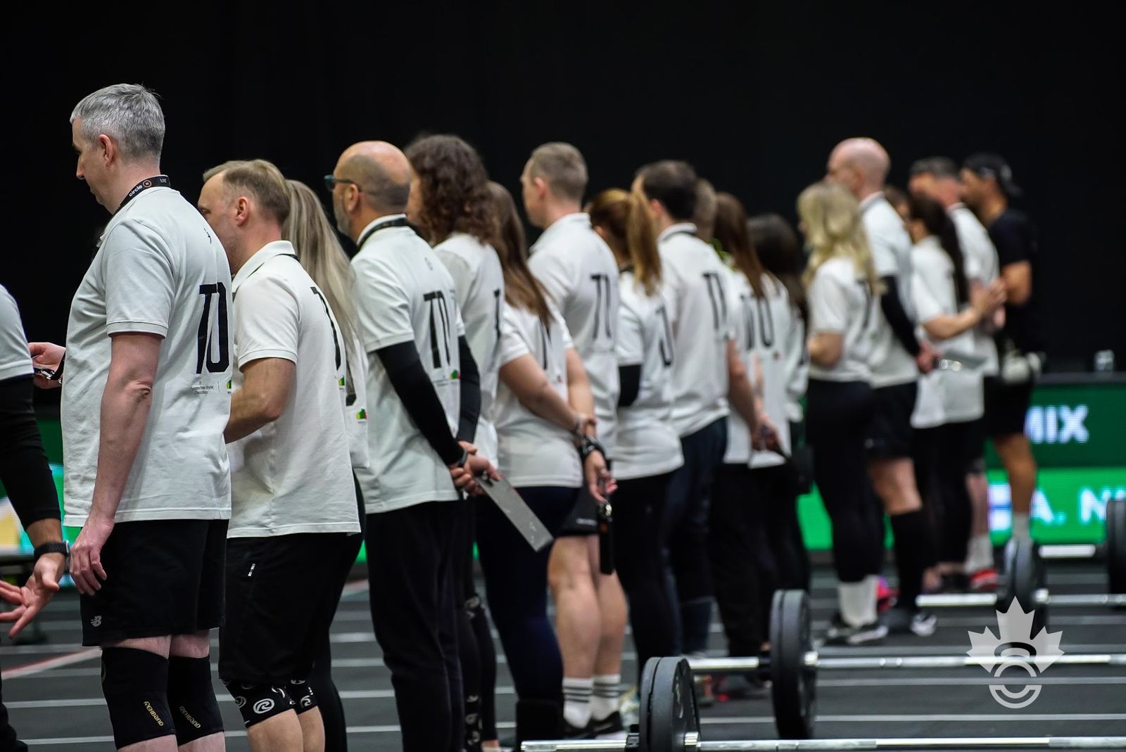 Technical Officials standing in a row along the competition floor, hands behind their backs, ready to judge